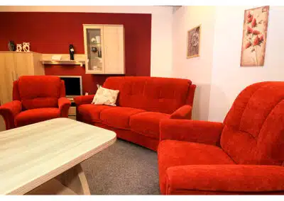 Rotes Sofa und Sessel vor einem Holztisch